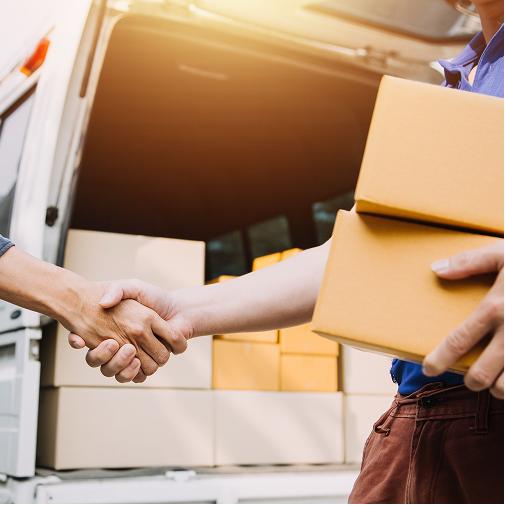 Two people shake hands near the open back of a van filled with cardboard boxes, with one person holding two boxes, suggesting a delivery or business agreement.