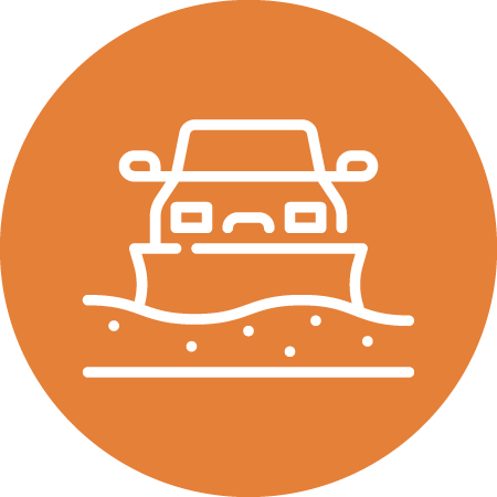 White line drawing of a car driving through floodwater, shown on an orange circular background. The car is partly submerged, indicating flooding or hazardous road conditions.