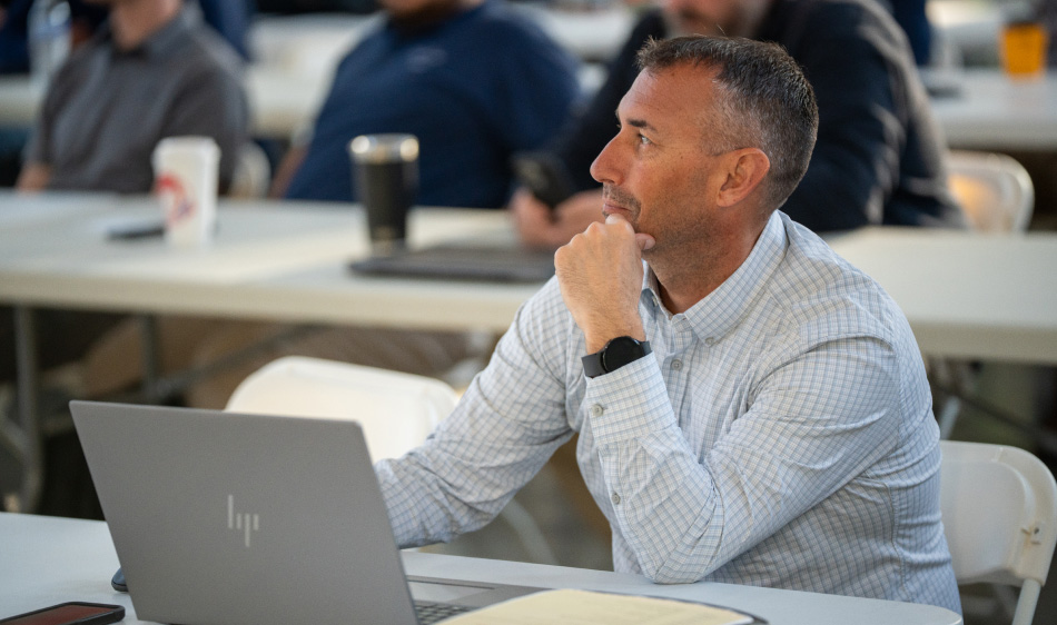 Adam Fowler sitting with a computer in front of him at a meeting